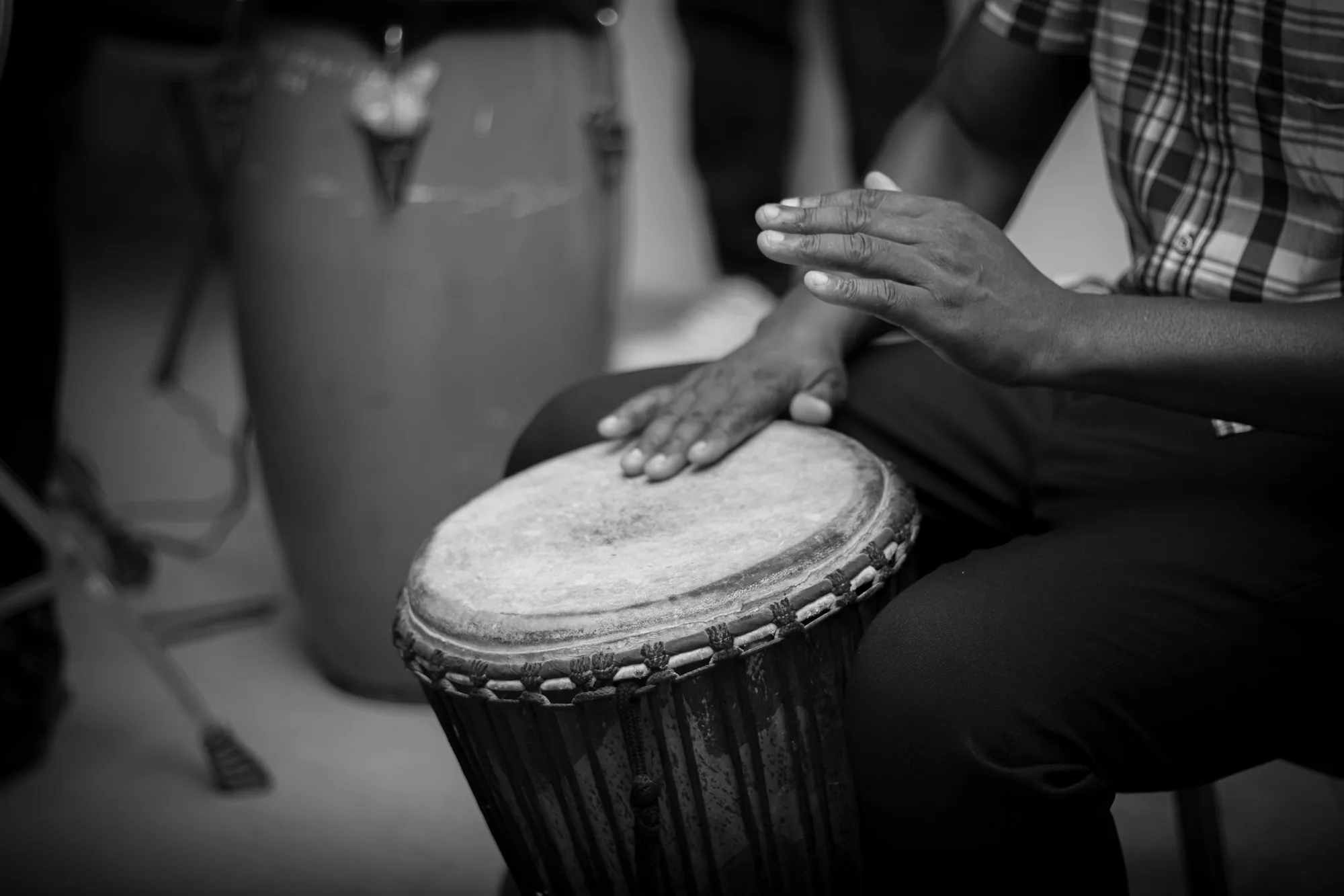 Mains d'un percussionniste sur la peau d'un djembé, en noir et blanc