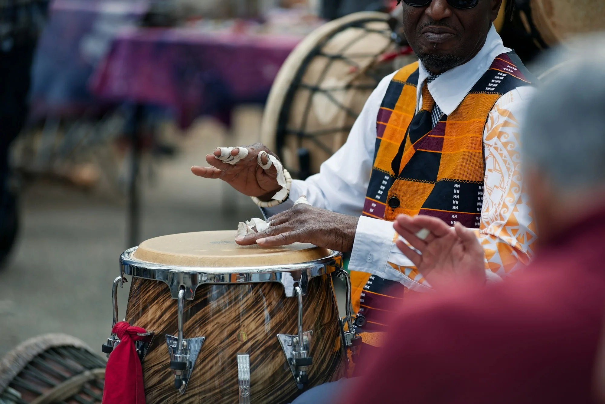 Percussionniste en gilet kente jouant du tambour, mains en mouvement