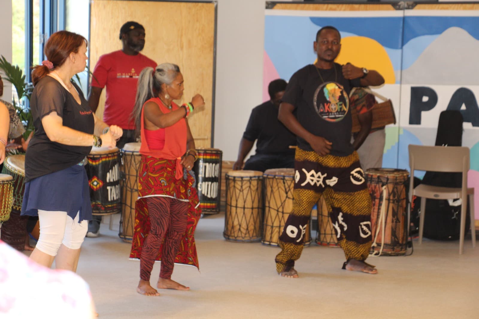 Deux danseur·ses d'AKOFA ASBL en pleine chorégraphie, fond coloré