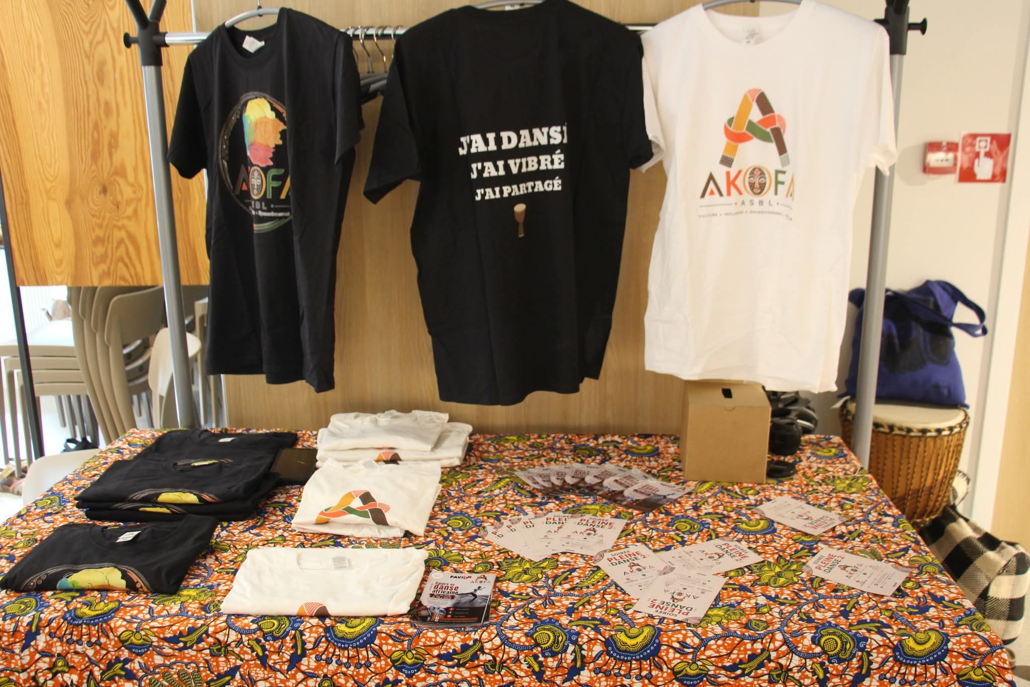 T-shirts et flyers AKOFA ASBL présentés sur un stand
